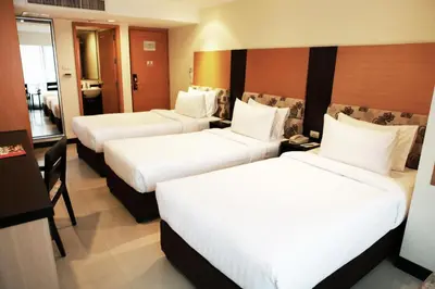 a hotel room with three beds with white sheets at Citin Pratunam Bangkok by Compass Hospitality in Bangkok