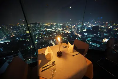 a table with a candle on a room with a view at Baiyoke Suite Hotel in Bangkok