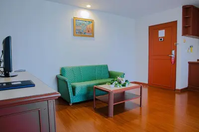 a living room with a green couch and a table at Baiyoke Suite Hotel in Bangkok