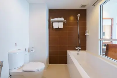 a bathroom with a tub and a toilet and a sink at Lantana Resort Hotel Bangkok in Bangkok