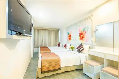 a hotel room with two beds and a flat screen tv at Pratunam City Inn in Bangkok