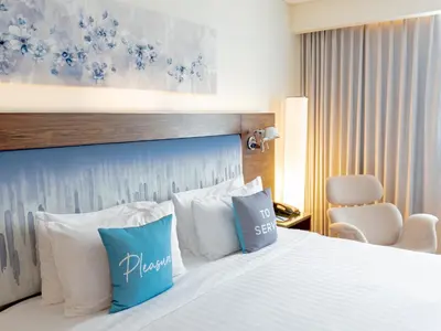 a hotel room with a bed with blue and white pillows at NH Bangkok Asoke in Bangkok