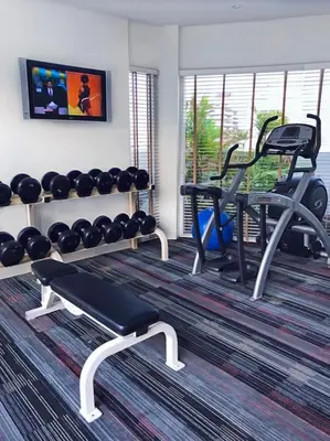 a fitness room with a gym with a bench and weights at NH Bangkok Asoke in Bangkok
