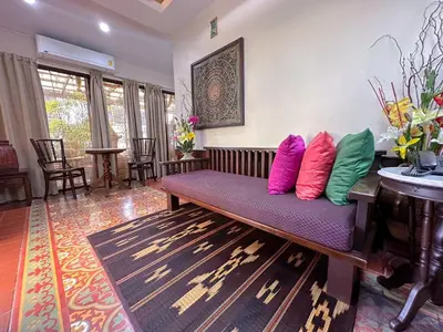 a living room with a bench with colorful pillows on it at The Siam Heritage Hotel in Bangkok