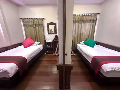 two beds with colorful pillows in a room at The Siam Heritage Hotel in Bangkok