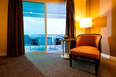 a room with a chair and a window with a balcony at Royal Princess Larn Luang - SHA Extra Plus in Bangkok