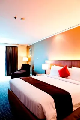 a hotel room with a large bed and a chair at Royal Princess Larn Luang - SHA Extra Plus in Bangkok