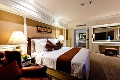 a hotel room with a large bed and a chair at Royal Princess Larn Luang - SHA Extra Plus in Bangkok
