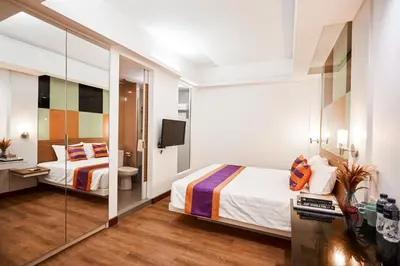 a hotel room with two beds and a mirror at Studio Asoke in Bangkok