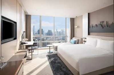 a hotel room with a large bed and a desk at Pathumwan Princess Hotel in Bangkok