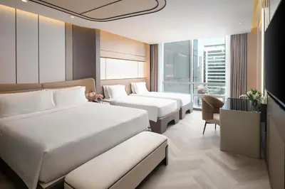 a hotel room with two beds and a window at Pathumwan Princess Hotel in Bangkok