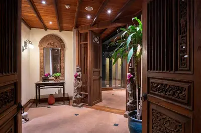 a hallway with a wooden door and a plant at Ariyasom Villa in Bangkok