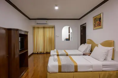 a hotel room with two beds and a television at The Victory Residences Bangkok in Bangkok