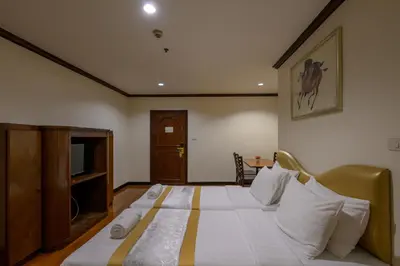 a bedroom with a bed with white sheets and a television at The Victory Residences Bangkok in Bangkok