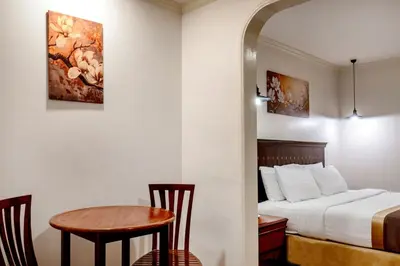 a hotel room with a bed and a table and chairs at The Victory Residences Bangkok in Bangkok
