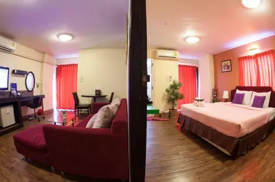 a bedroom with a bed and a couch and a tv at Vabua Asotel Bangkok in Bangkok