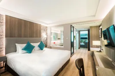 a bedroom with a large white bed with blue pillows at Citrus Suites Sukhumvit 6 by Compass Hospitality in Bangkok