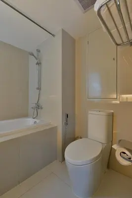 a white bathroom with a toilet and a bath tub at Le D'Tel Bangkok in Bangkok