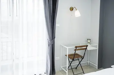 a bedroom with a desk and a chair next to a window at Twentynine KV Apartel in Nonthaburi