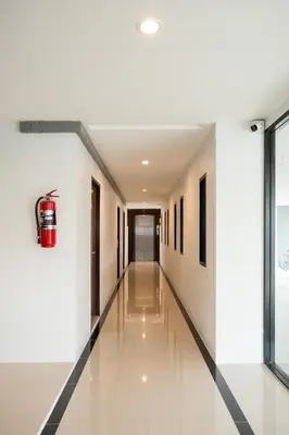an empty hallway in a building with a fire extinguisher at Twentynine KV Apartel in Nonthaburi
