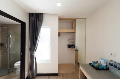 a bathroom with a shower and a toilet and a window at Tarawish Hotel in Bangkok