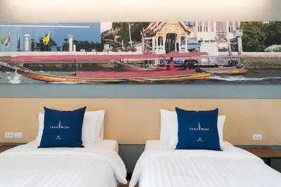 two beds in a hotel room with a picture of a boat at Tarawish Hotel in Bangkok