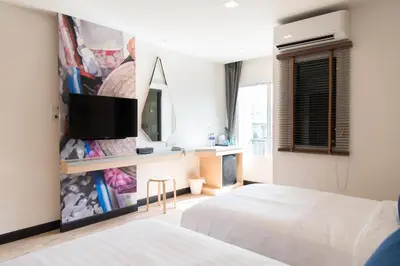 a bedroom with two beds and a tv on a wall at Tarawish Hotel in Bangkok