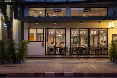 people sitting at tables outside of a restaurant at night at Yaks House Hostel in Bangkok