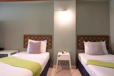 a room with two beds and a table with a lamp at Collection O Howard Square Boutique Hotel in Bangkok