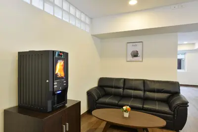 a living room with a black leather couch and a television at Studio Residence Sukhumvit 71 in Bangkok