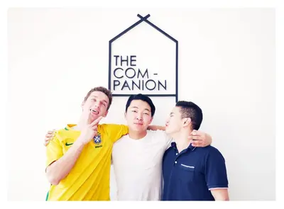 three men standing under a sign that reads the cornantom at The Companion in Bangkok