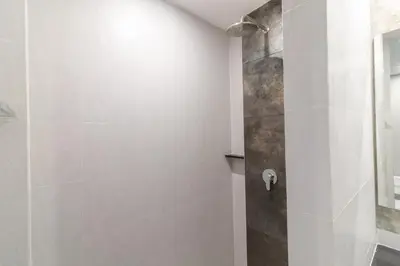 a bathroom with a shower with white tiles at Zleepmotion Bangkok in Bangkok