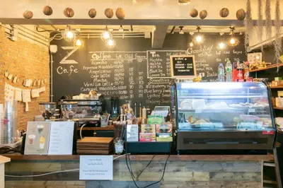a coffee shop with a black wall with a menu at Zleepmotion Bangkok in Bangkok
