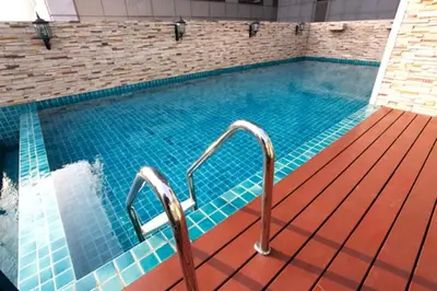 a swimming pool with blue tiles on a wooden deck at Rongratana Executive Residence Bangkok in Bangkok