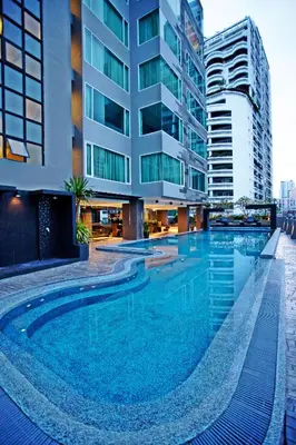 a large swimming pool in front of a building at Golden Tulip Mandison Suites in Bangkok