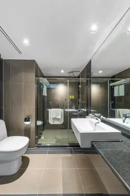 a bathroom with a toilet and a sink and a shower at Golden Tulip Mandison Suites in Bangkok