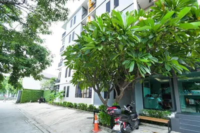 a motorcycle parked next to a tree next to a building at Sleep Hotel Bangkok in Bangkok