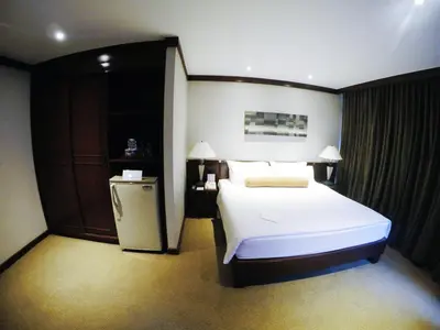 a bedroom with a bed and a small refrigerator at City Lodge Bangkok in Bangkok