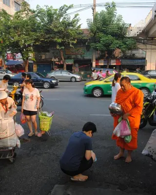 a monk in an orange robe standing in a street at Focal Local Bed & Breakfast in Bangkok