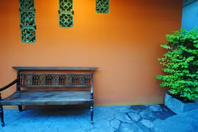 a wooden bench sitting next to a orange wall at Focal Local Bed & Breakfast in Bangkok