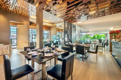 a dining room with tables and chairs and windows at M2 de Bangkok Hotel in Bangkok