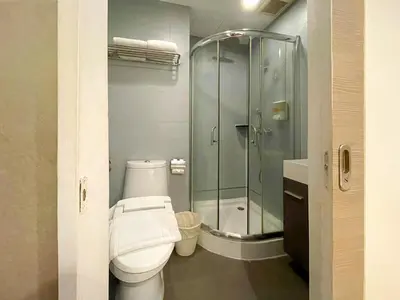 a bathroom with a toilet and a glass shower at Arawana Express Phromphong in Bangkok