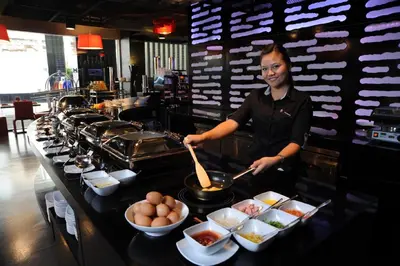 a chef preparing food at a counter in a restaurant at Galleria 10 Hotel Bangkok in Bangkok