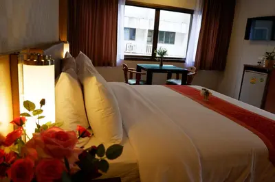 a hotel room with a bed with white pillows and flowers at Dynasty Inn in Bangkok