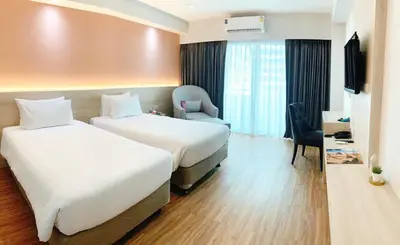 a hotel room with two beds and a television at Miloft Sathorn Hotel in Bangkok