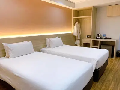 two beds in a hotel room with white sheets at Miloft Sathorn Hotel in Bangkok