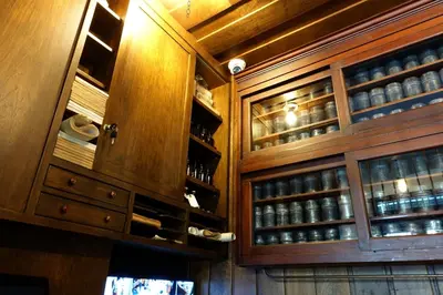 a kitchen with wooden cabinets and shelves with glasses at 1905 Heritage Corner in Bangkok
