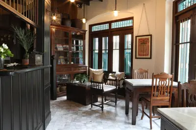 a dining room with a table and chairs and windows at 1905 Heritage Corner in Bangkok