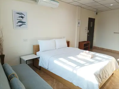 a bedroom with a large white bed and a couch at Double D Rooms & Cafe in Bangkok