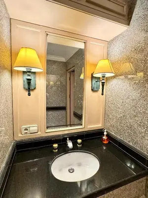 a bathroom with a sink with two lamps and a mirror at Royal Benja Hotel - Big Rooms, Family Friendly in Bangkok